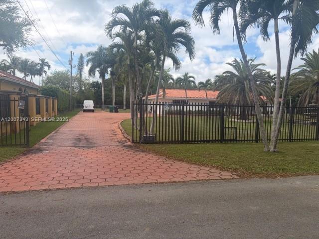 A paved driveway leads to a gated residential property with palm trees and a house — 7090 SW 62nd St # 0, Miami FL 33143, MIAMI, FL