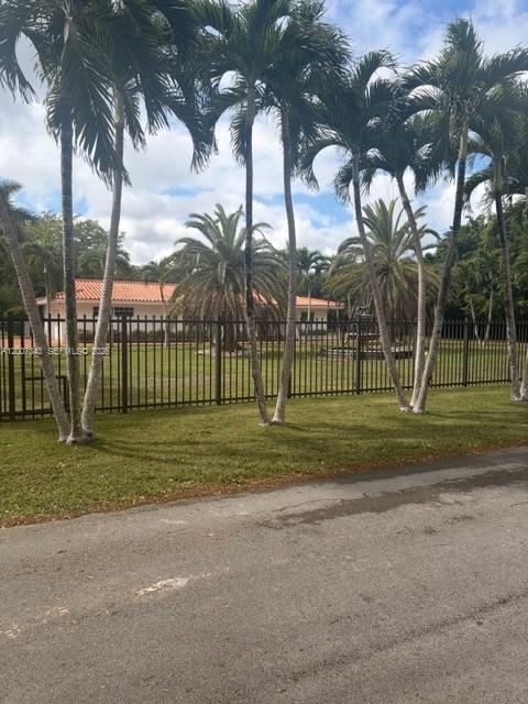 A single-story house with a terracotta roof sits behind a black metal fence and palms — 7090 SW 62nd St # 0, Miami FL 33143, MIAMI, FL
