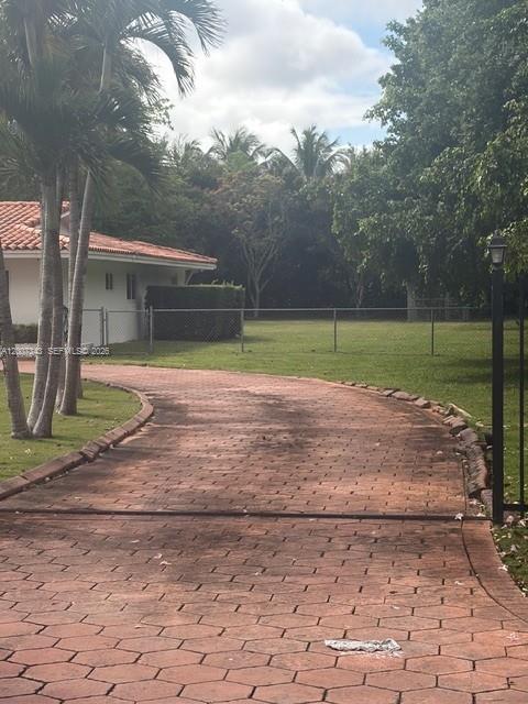 A paved hexagonal brick driveway leads toward a house with a tiled roof and palm trees — 7090 SW 62nd St # 0, Miami FL 33143, MIAMI, FL