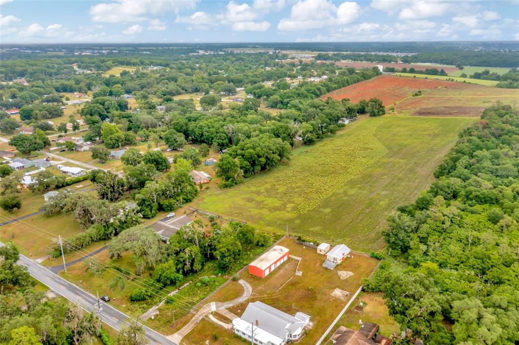 An aerial view shows a rural property with several buildings, a large field, and surrounding trees — FORT KING RD ROAD, DADE CITY, FL