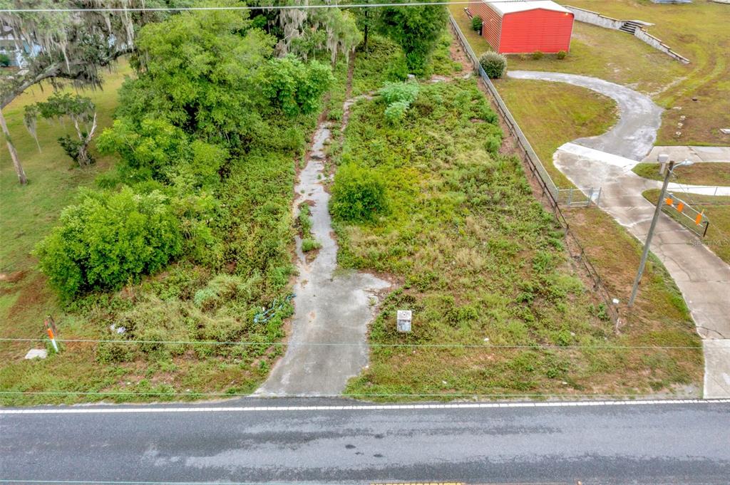 An aerial view shows a narrow, overgrown vacant lot with a concrete driveway near a road — FORT KING RD ROAD, DADE CITY, FL