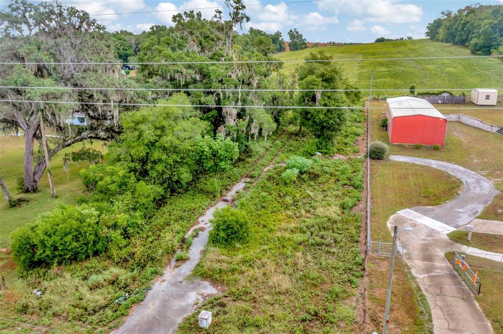 An aerial view shows a grassy lot with trees, a red metal building, and a driveway — FORT KING RD ROAD, DADE CITY, FL