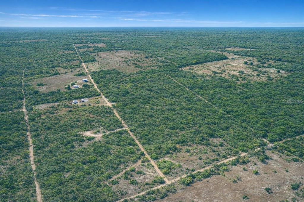 An aerial view shows a dirt road running through a vast, sparsely developed scrubland area — NE 56TH STREET, BRONSON, FL