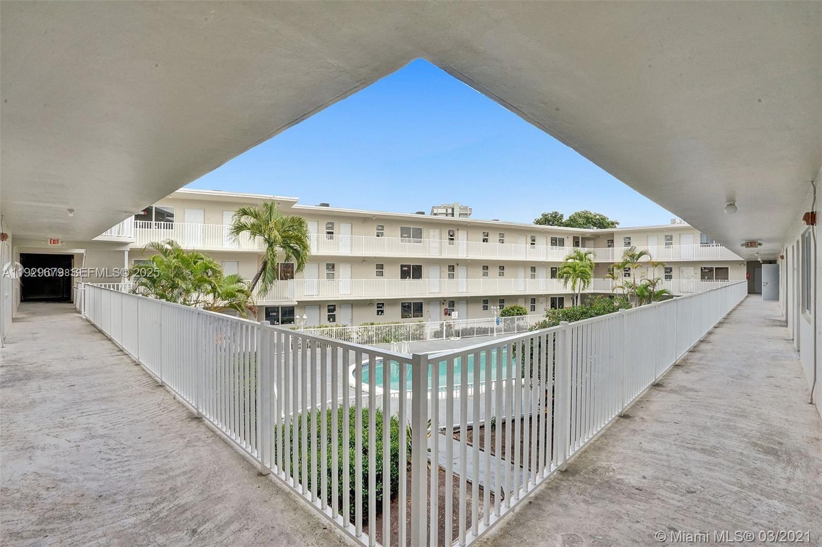 An outdoor walkway overlooks a courtyard with a swimming pool at a multi-story apartment complex — 1895 Venice Park Dr # A18, Miami FL 33181, MIAMI, FL