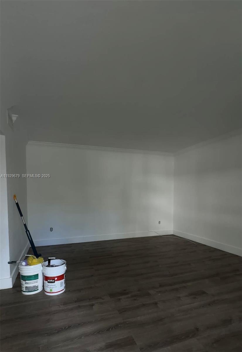An empty room features white walls, dark wood-look flooring, and two paint buckets — 1895 Venice Park Dr # A18, Miami FL 33181, MIAMI, FL