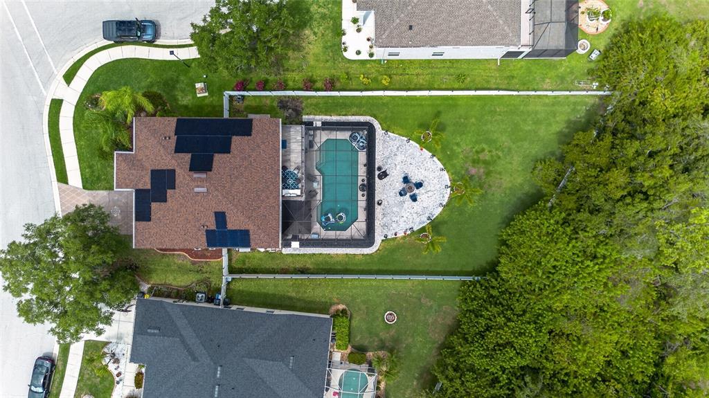 An aerial view shows a house with solar panels, a screened pool, and a backyard patio — 11384 WALDEN LOOP, PARRISH, FL