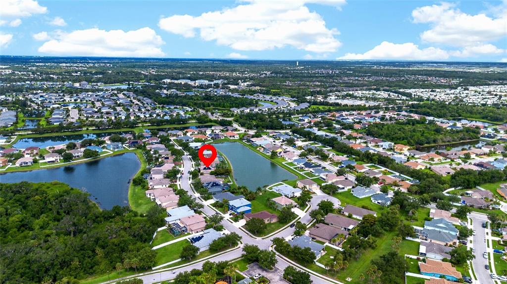 This is an aerial view of a residential neighborhood featuring houses surrounding a central lake — 11384 WALDEN LOOP, PARRISH, FL