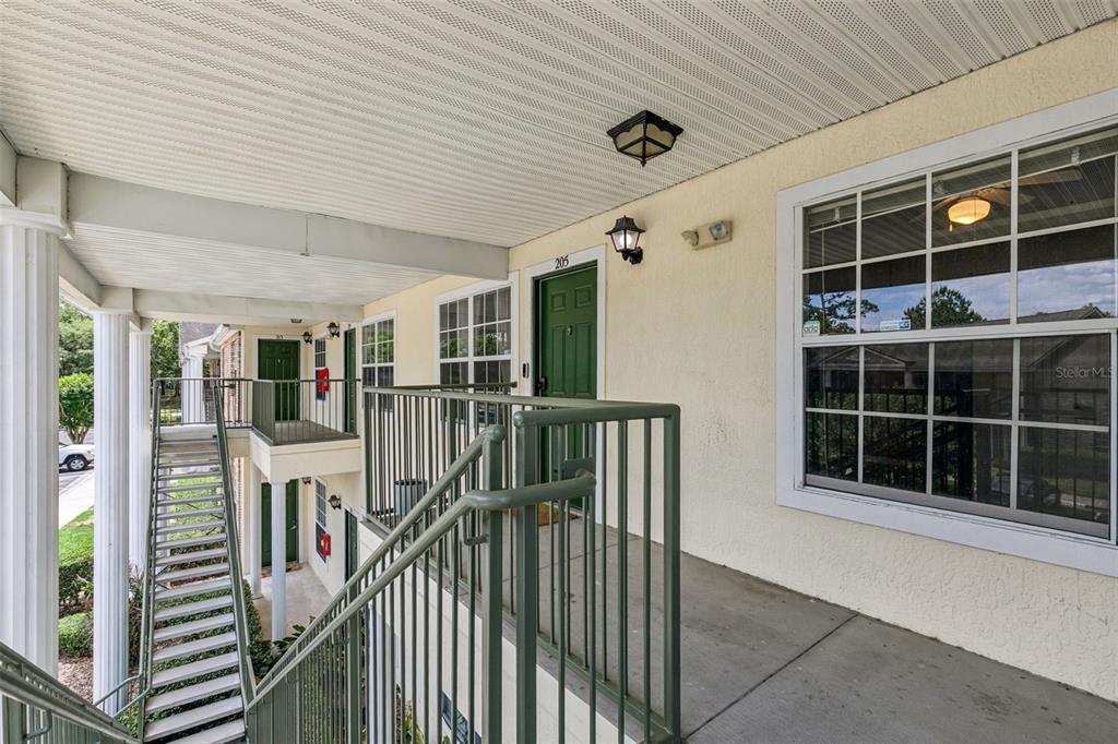 An exterior view of an apartment building walkway with green doors and metal railings — 145 RESERVE CIRCLE UNIT 205, OVIEDO, FL