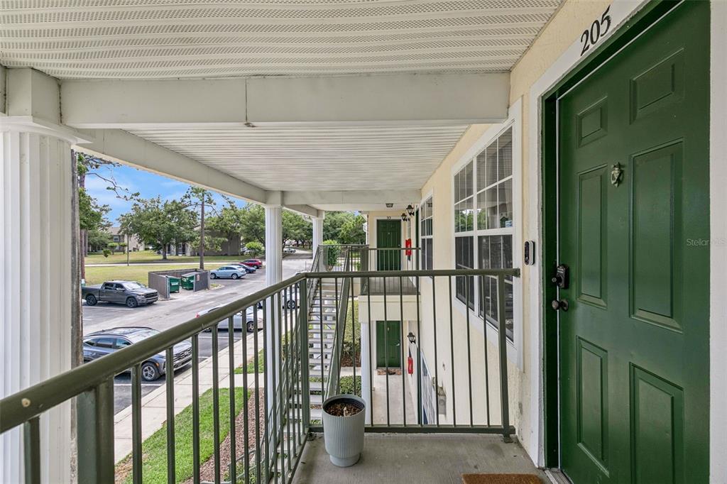 An outdoor apartment balcony with a green door, metal railing, and a view of parking — 145 RESERVE CIRCLE UNIT 205, OVIEDO, FL