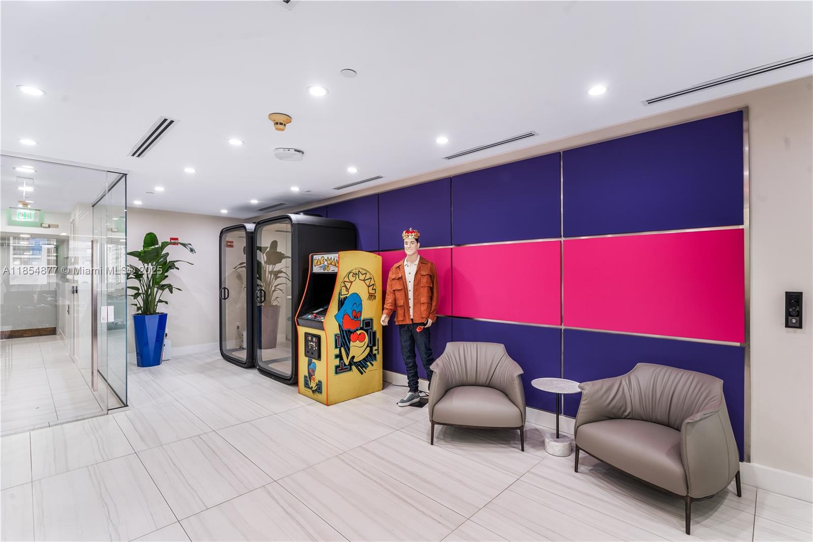 A modern office lobby features a Pac-Man arcade cabinet, a mannequin, and two lounge chairs — 1200 Brickell Ave # A, Miami FL 33131, MIAMI, FL