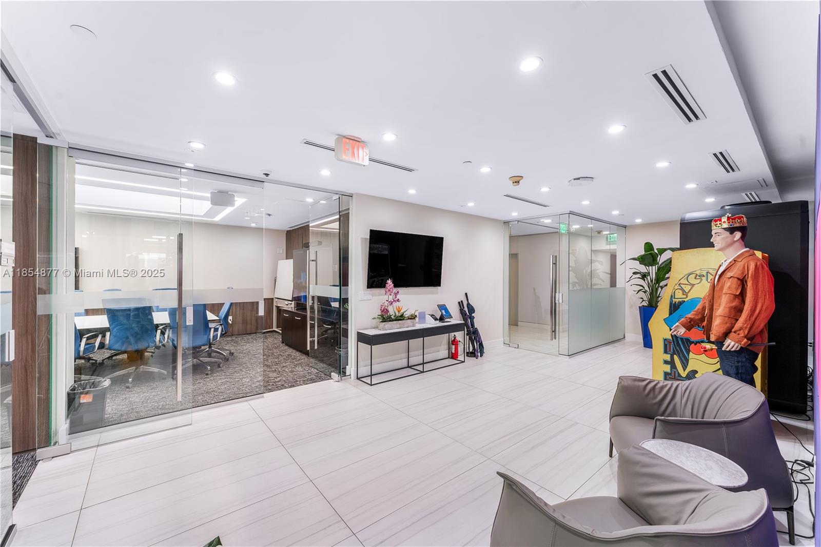 A modern office lobby features glass-walled conference rooms, tiled floors, and a Pac-Man arcade cabinet — 1200 Brickell Ave # A, Miami FL 33131, MIAMI, FL
