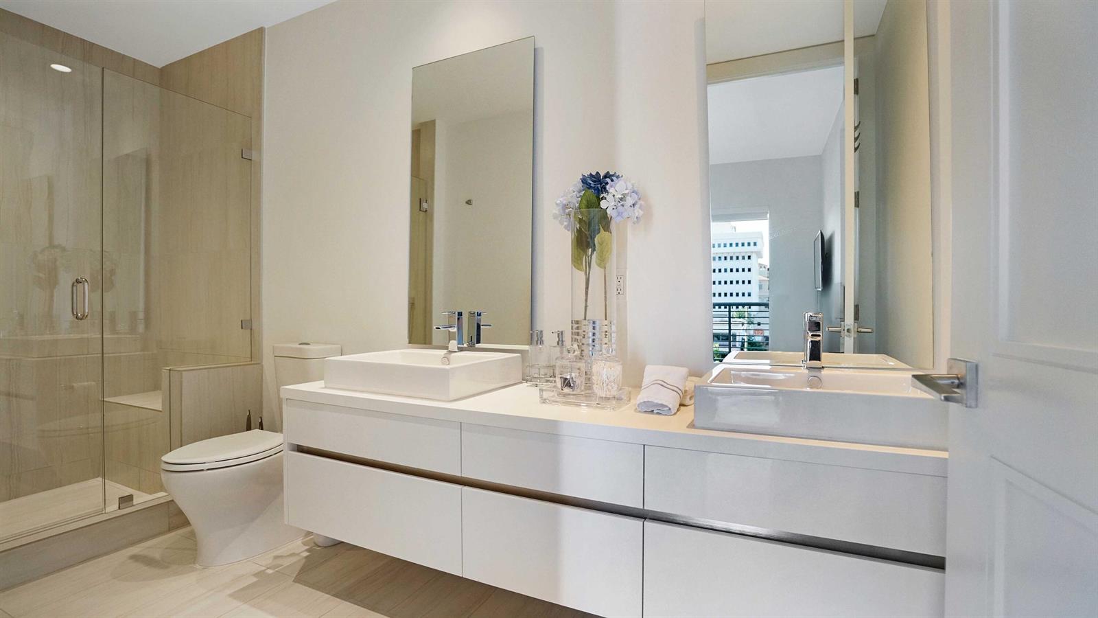 A modern bathroom features a double vanity with white vessel sinks and a glass shower — 155 E Boca Raton Road # 501, Boca Raton FL 33432, BOCA RATON, FL