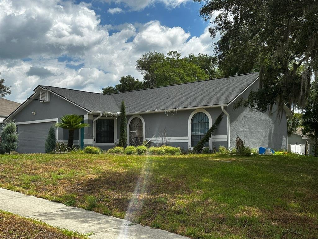 A gray, single-story house with a shingled roof, arched windows, and a front lawn — 409 ELKIN AVENUE, DELTONA, FL