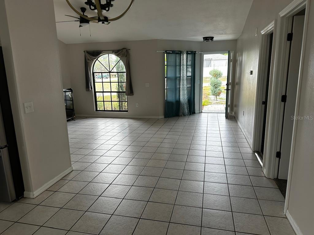 An open living area features light-colored tile flooring, an arched window, and a glass-paneled door — 409 ELKIN AVENUE, DELTONA, FL