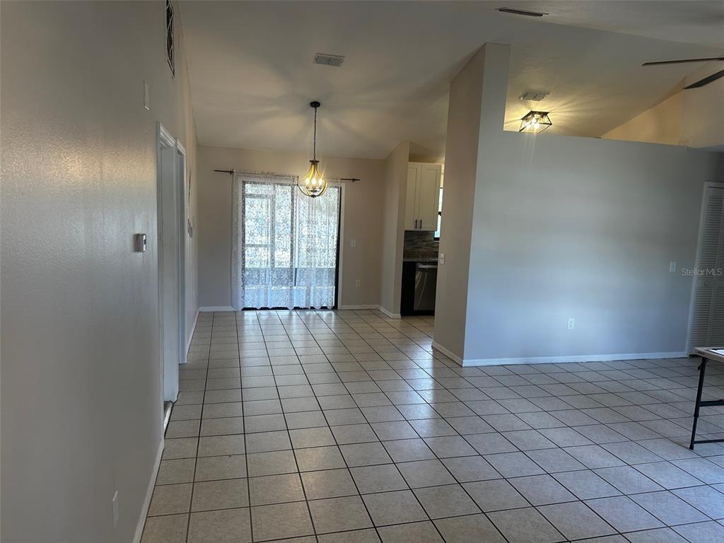 A tiled dining area features a hanging light fixture and sliding glass doors to a patio — 409 ELKIN AVENUE, DELTONA, FL