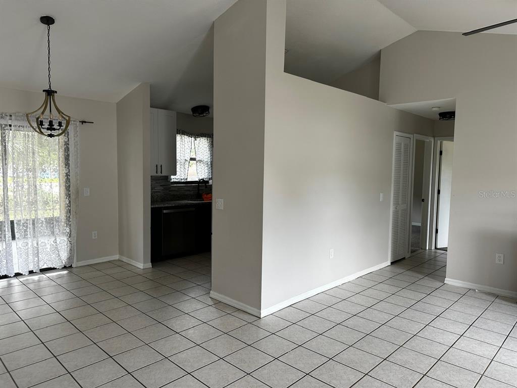 A tiled dining area leads to a kitchen with white cabinets and dark countertops — 409 ELKIN AVENUE, DELTONA, FL