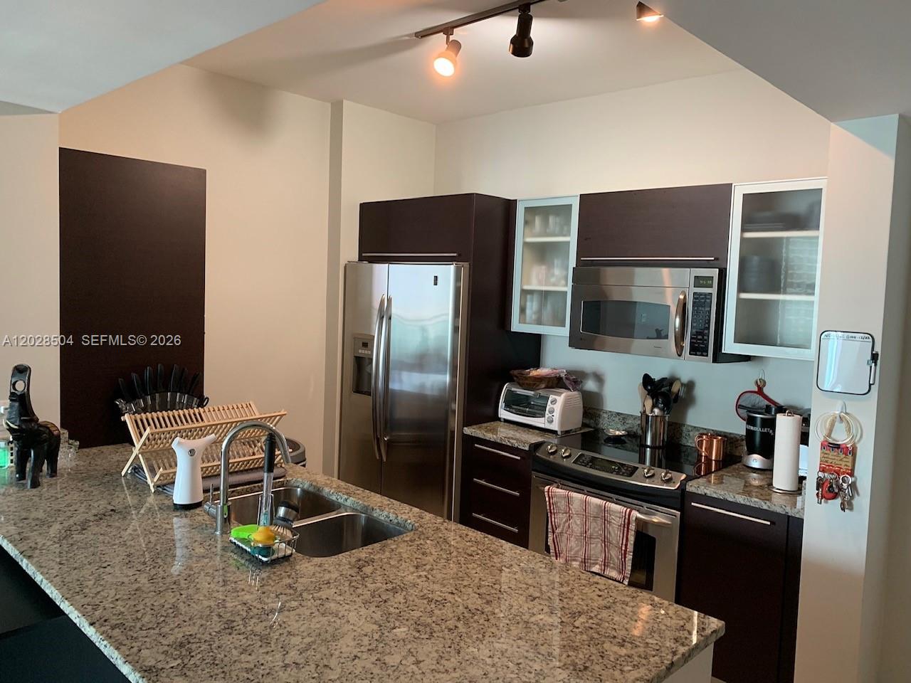 A kitchen features dark wood cabinets, granite countertops, stainless steel appliances, and a central island — 951 Brickell Ave # 4005, Miami FL 33131, MIAMI, FL