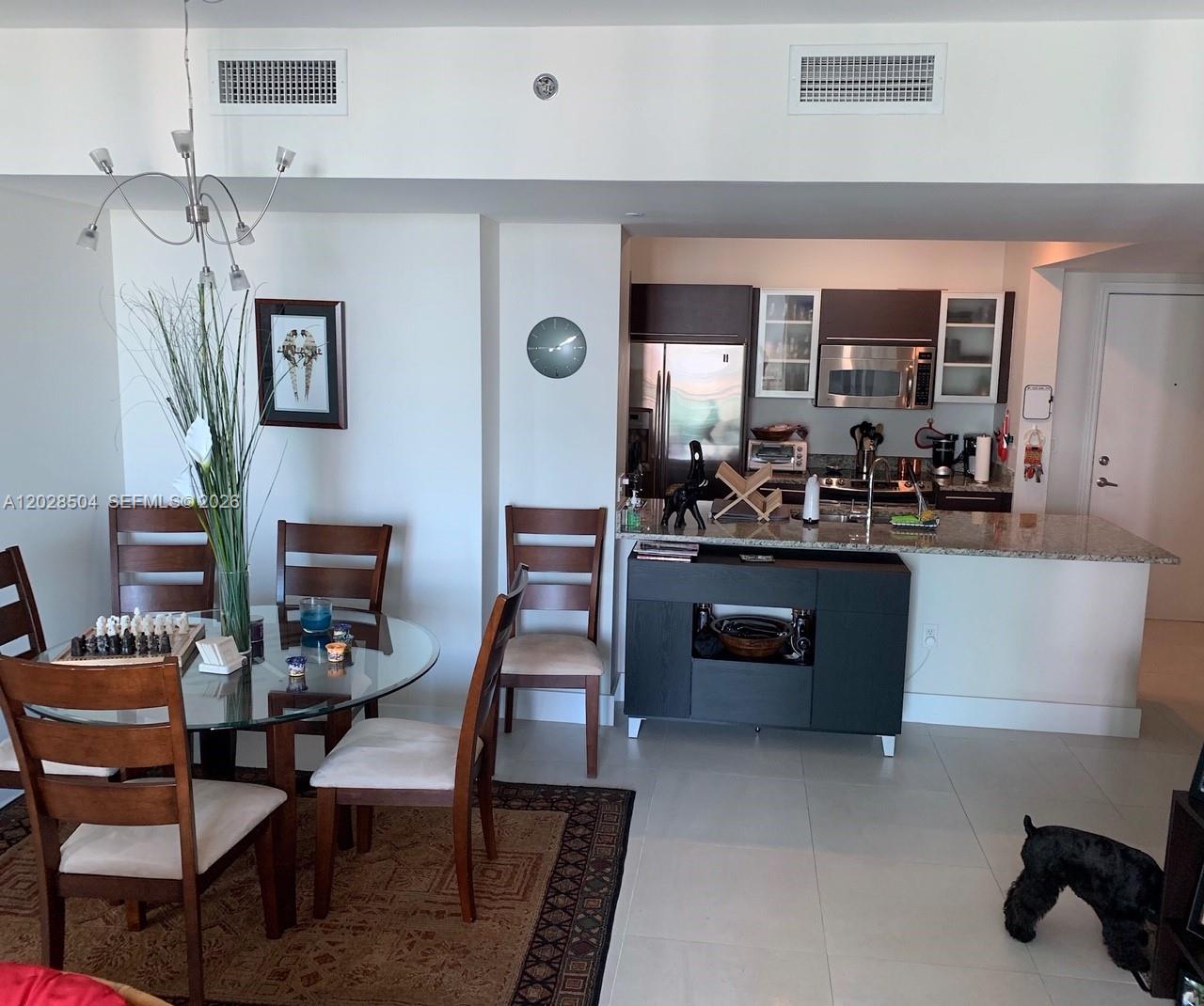 A dining area with a glass table sits adjacent to an open kitchen with dark cabinetry — 951 Brickell Ave # 4005, Miami FL 33131, MIAMI, FL