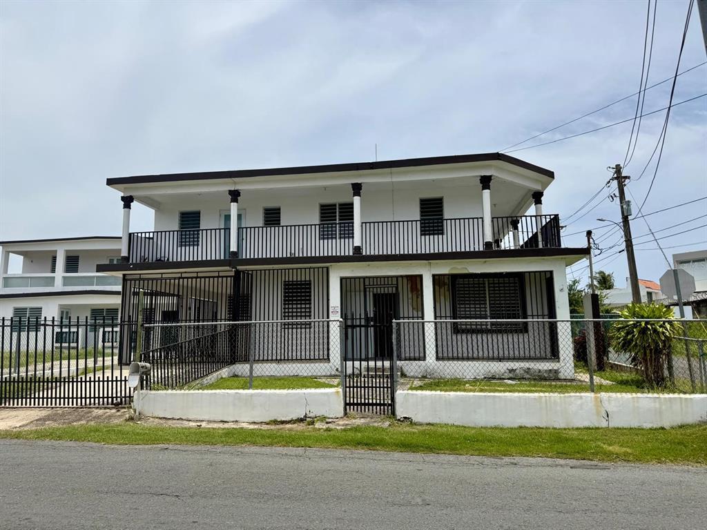 A two-story house with a balcony, metal security bars, and a chain-link fence — 53 CALLE SATURNO COM SANDIN UNIT 1, VEGA BAJA, PR