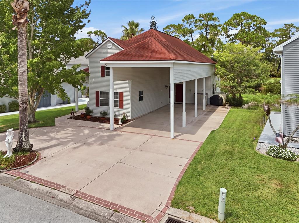 An exterior view of a two-story house featuring a large attached carport and red roof — 523 FAIRWAYS DRIVE UNIT 523, TITUSVILLE, FL