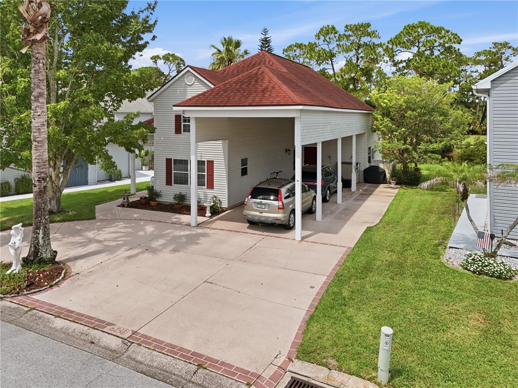 An exterior view of a two-story house with a large attached carport and concrete driveway — 523 FAIRWAYS DRIVE UNIT 523, TITUSVILLE, FL
