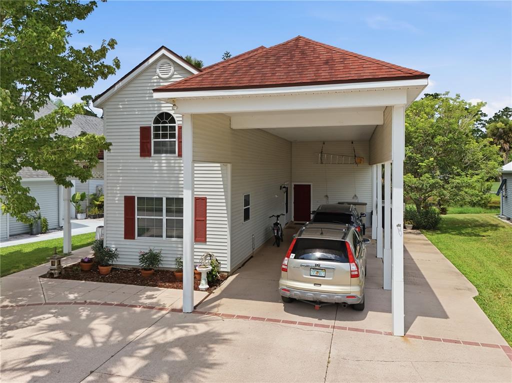 A two-story house features a large attached carport and a concrete driveway — 523 FAIRWAYS DRIVE UNIT 523, TITUSVILLE, FL