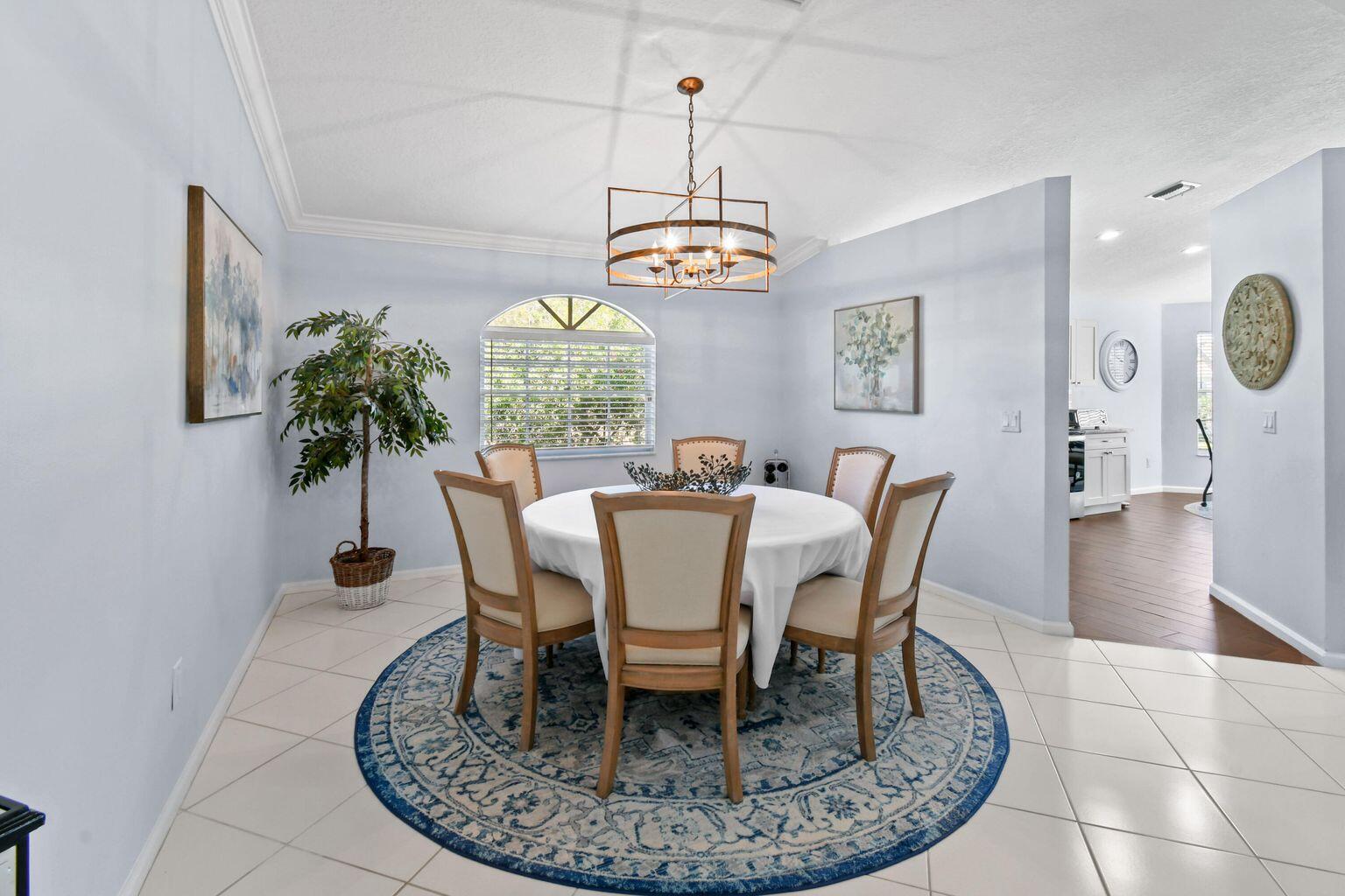 A dining room with a round table, six chairs, a blue rug, and a chandelier — 252 Legendary Circle, Palm Beach Gardens FL 33418, PALM BEACH GARDENS, FL