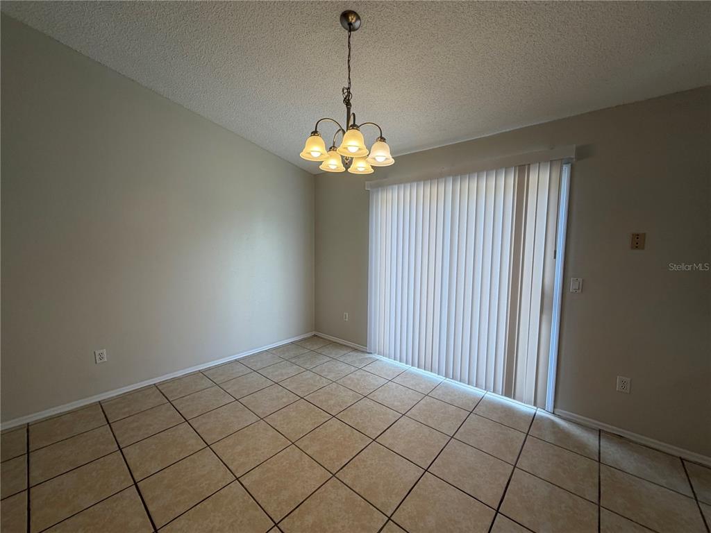 A dining area features beige walls, light-colored floor tiles, a chandelier, and vertical sliding glass doors — 73 OLIVE DRIVE, OCALA, FL