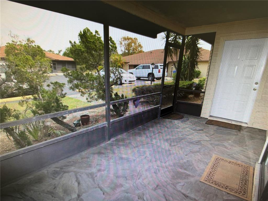 A single-story house with beige siding, a screened-in entryway, and a landscaped front yard — 4161 66TH STREET CIRCLE W, BRADENTON, FL