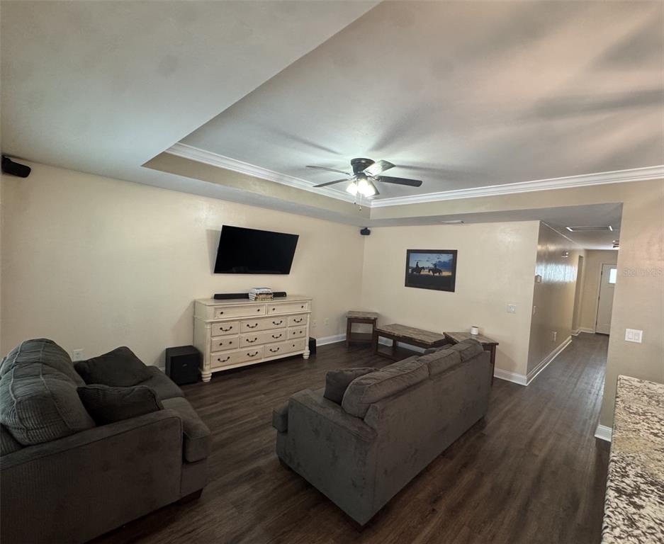 A living room features gray sofas, a white dresser media console, and dark wood flooring — 8291 NE 118TH TERRACE, BRONSON, FL