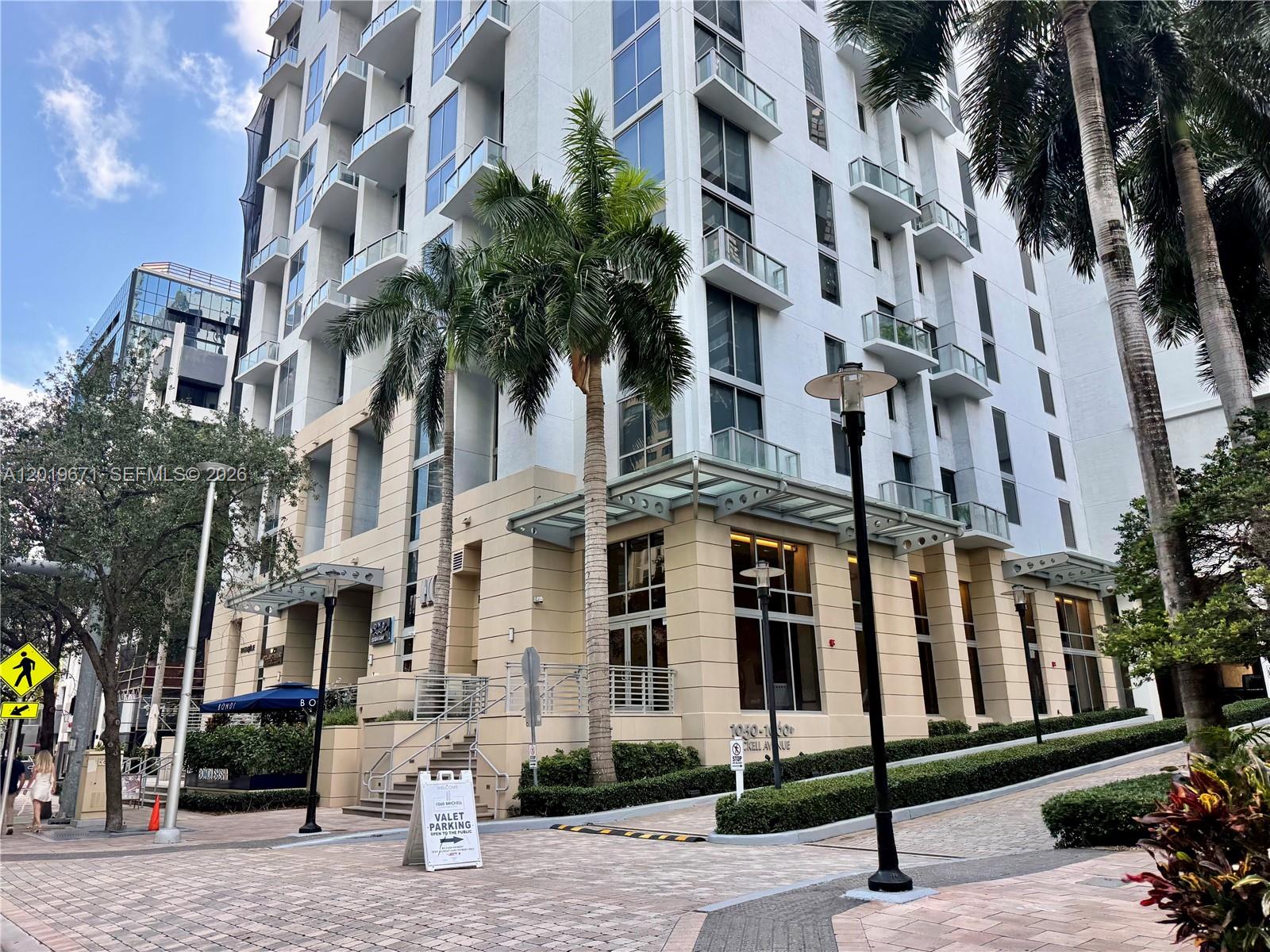 A multi-story residential building with balconies, palm trees, and a valet parking sign outside — 1060 Brickell Ave # 2409, Miami FL 33131, MIAMI, FL