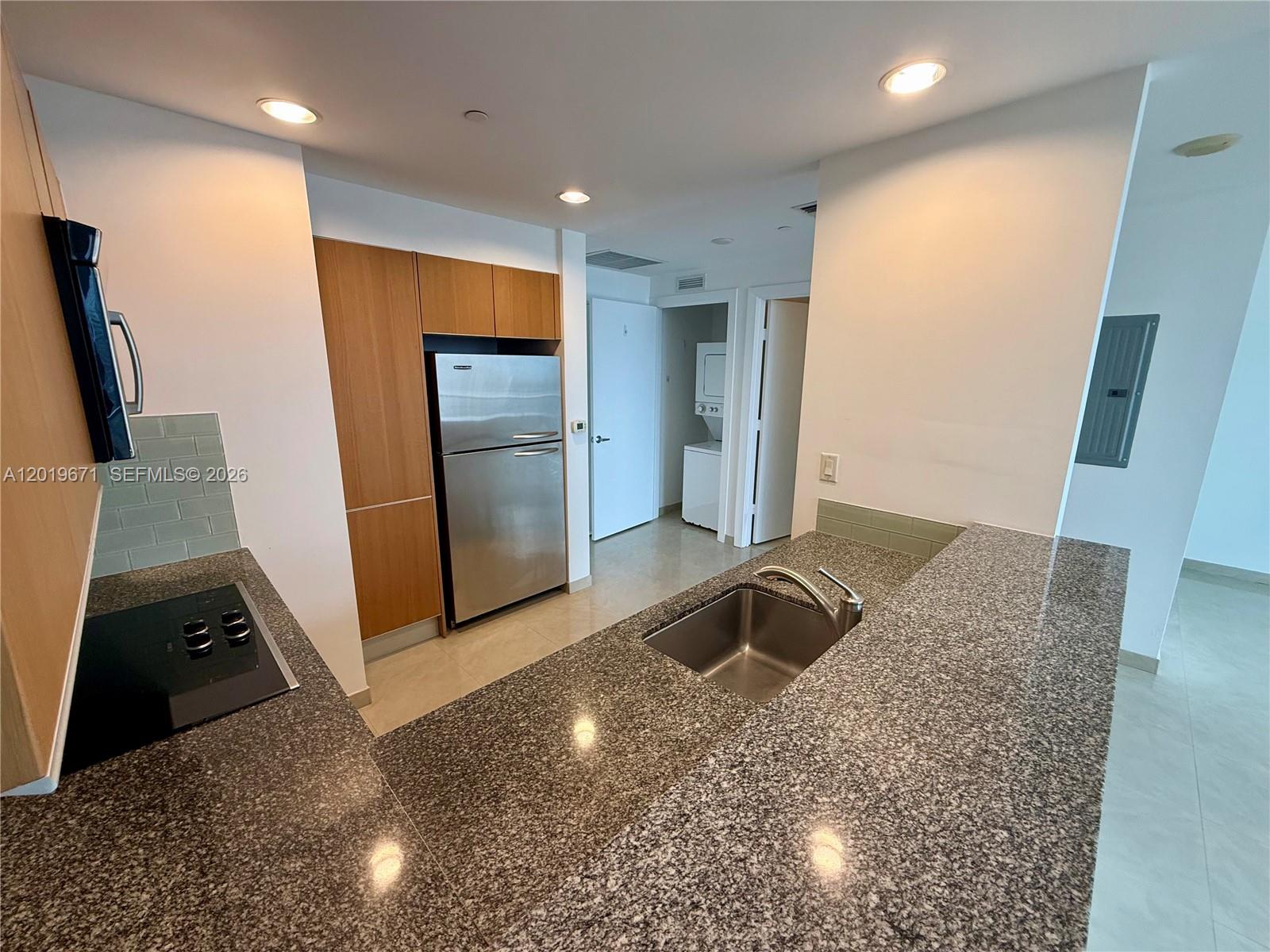 A kitchen features granite countertops, stainless steel appliances, and light wood cabinetry — 1060 Brickell Ave # 2409, Miami FL 33131, MIAMI, FL
