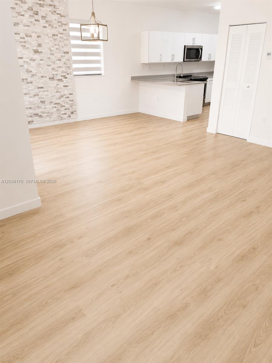 This open-concept kitchen and dining area features light wood-look flooring and a stone accent wall — 15560 SW 136th St # 201, Miami FL 33196, MIAMI, FL