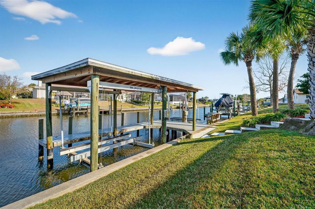 A boat lift with a wooden roof sits over a canal next to a grassy lawn — 10 FLEMING COURT, PALM COAST, FL