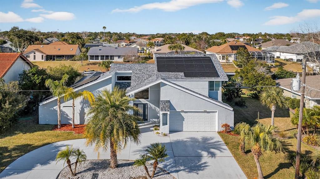 An aerial view of a gray house with solar panels on a shingled roof — 10 FLEMING COURT, PALM COAST, FL