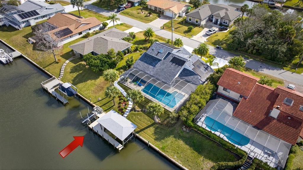 An aerial view shows a waterfront home with a private dock, boat lift, and pool — 10 FLEMING COURT, PALM COAST, FL