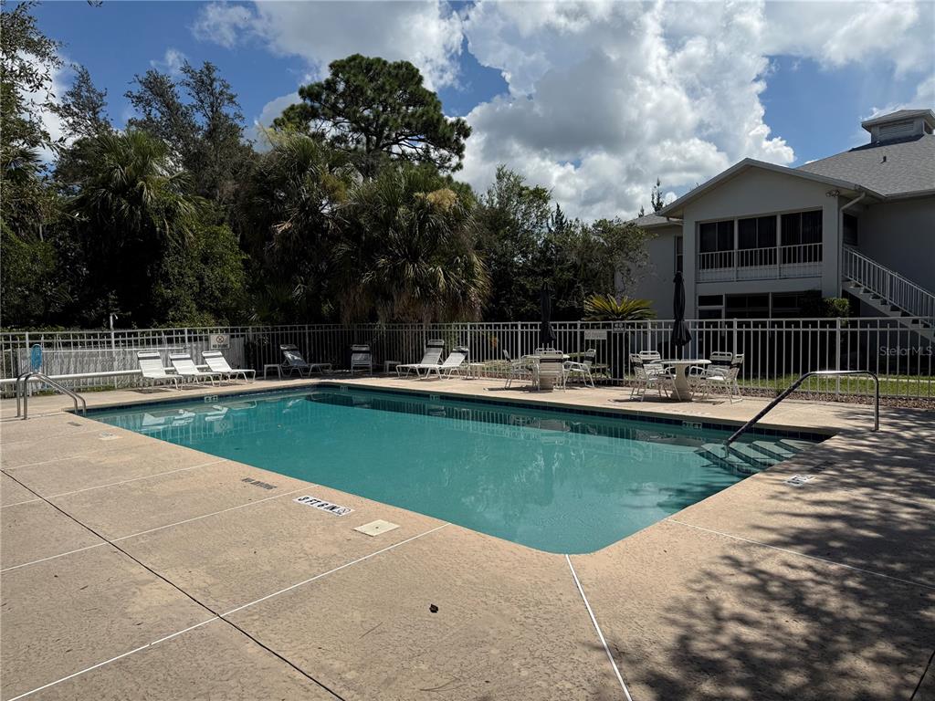 An outdoor swimming pool surrounded by a concrete deck, lounge chairs, and a residential building — 857 SE MAYO DRIVE UNIT 102, CRYSTAL RIVER, FL