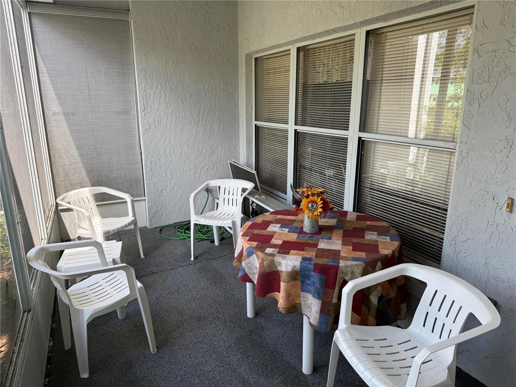 A screened-in patio features a round table with a patterned cloth and four white chairs — 857 SE MAYO DRIVE UNIT 102, CRYSTAL RIVER, FL