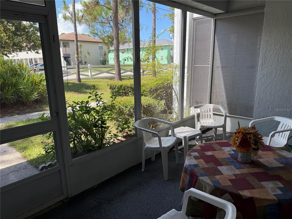 A screened-in patio features white plastic chairs, a small table, and a patterned tablecloth — 857 SE MAYO DRIVE UNIT 102, CRYSTAL RIVER, FL