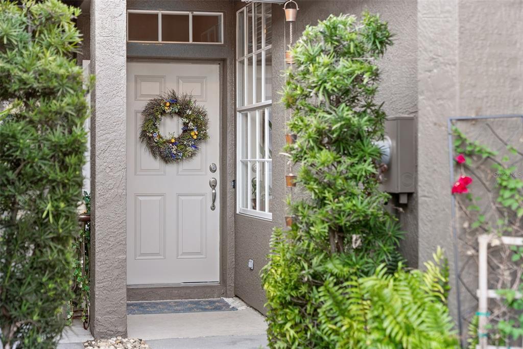 A front entrance features a light-colored door with a wreath, a window, and surrounding greenery — 5357 60TH AVENUE N, ST PETERSBURG, FL