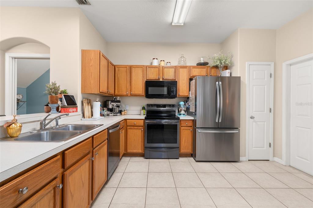 A kitchen features oak cabinets, stainless steel appliances, a double sink, and tile flooring — 5357 60TH AVENUE N, ST PETERSBURG, FL