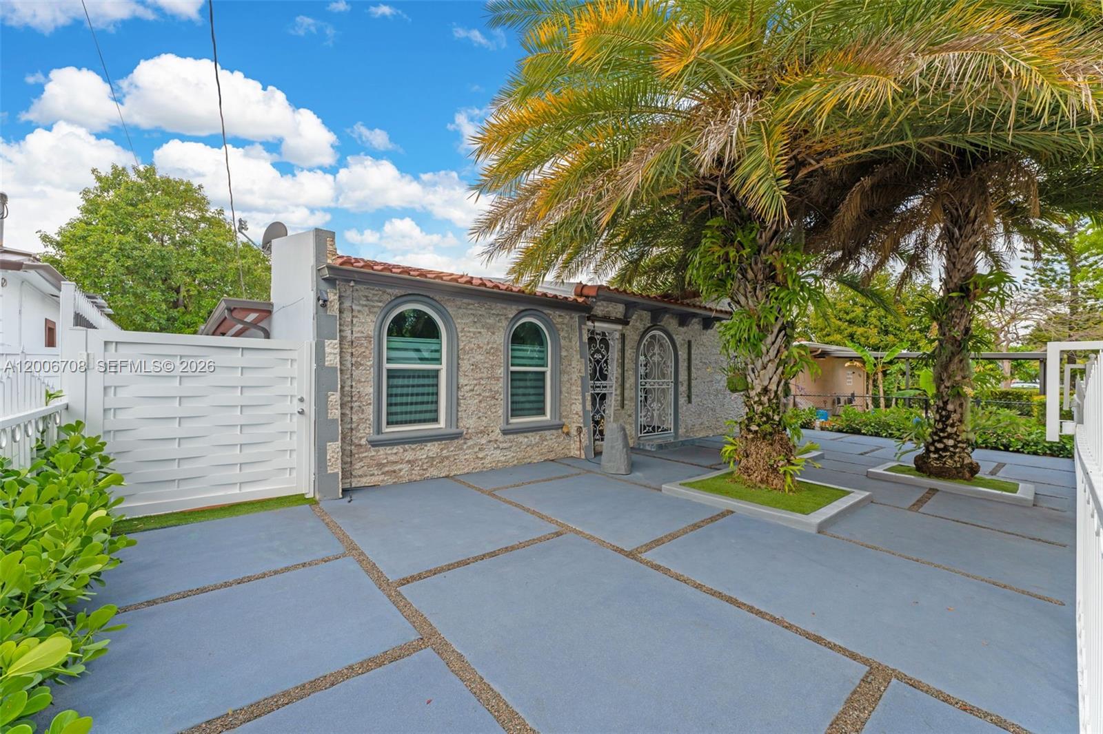 A stone-faced house features arched windows and a paved driveway with two palm trees — 1870 NW 32nd Ave, Miami FL 33125, MIAMI, FL