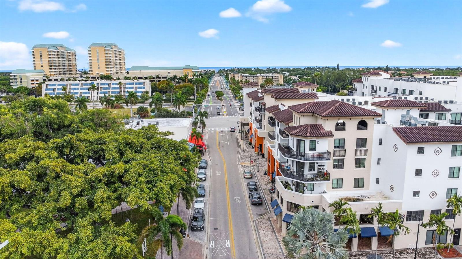An aerial view shows a street lined with modern buildings, palm trees, and parked cars — 510 E Ocean Avenue # 102, Boynton Beach FL 33435, BOYNTON BEACH, FL