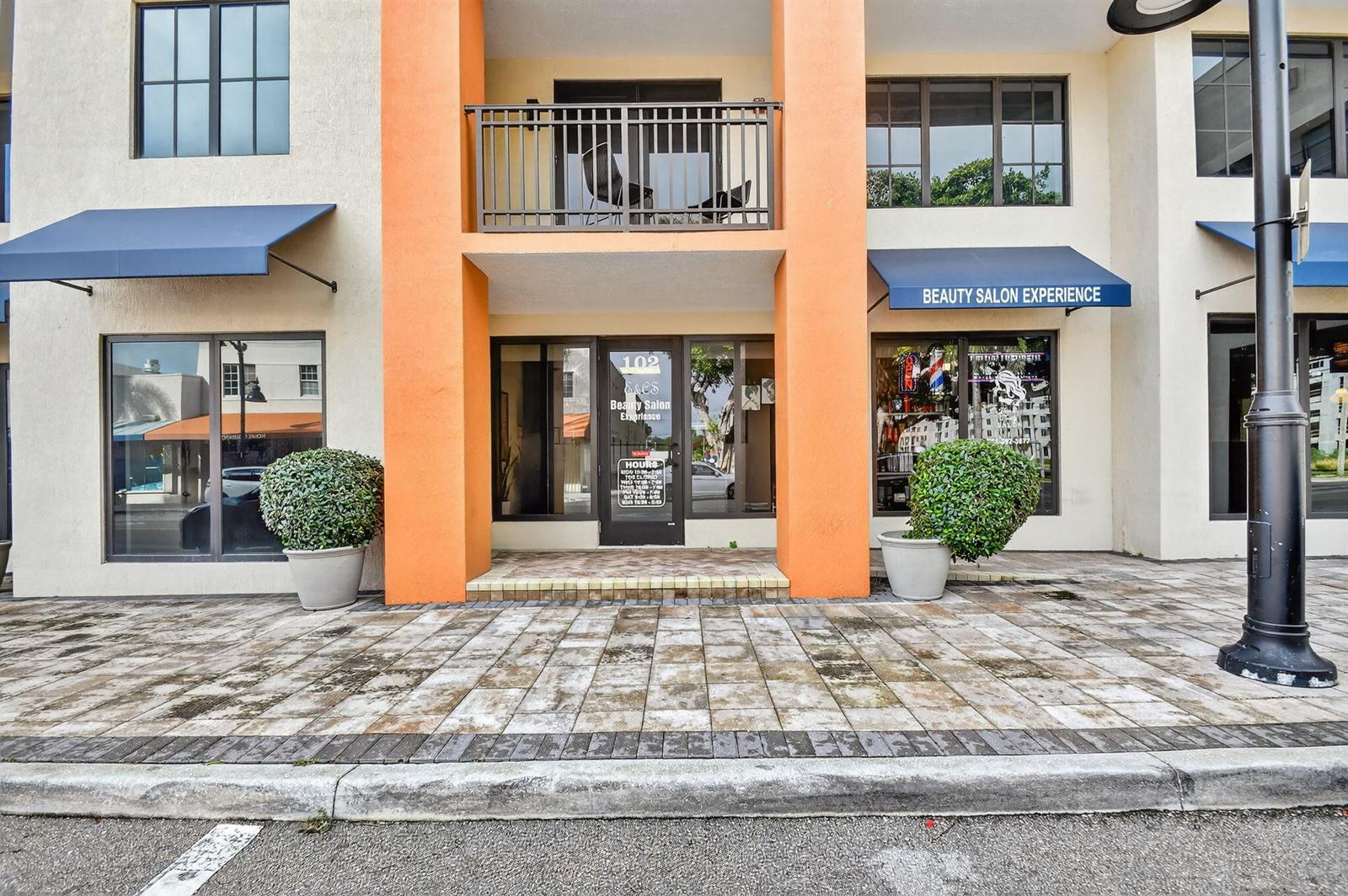 The exterior of a commercial building features a central entrance with orange pillars and balconies — 510 E Ocean Avenue # 102, Boynton Beach FL 33435, BOYNTON BEACH, FL
