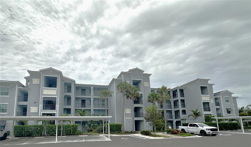 A multi-story gray apartment building with a covered parking area and a white pickup truck — 14121 HERITAGE LANDING BOULEVARD UNIT 743, PUNTA GORDA, FL