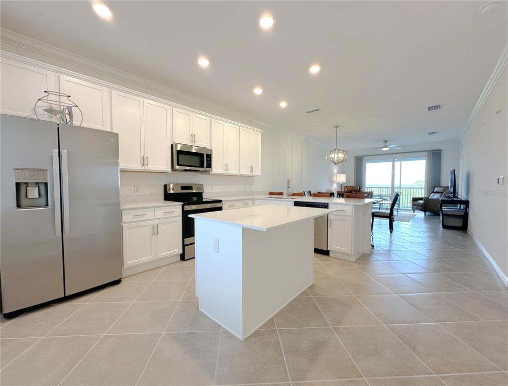 An open-concept living and dining area features tile flooring, a ceiling fan, and neutral walls — 14121 HERITAGE LANDING BOULEVARD UNIT 743, PUNTA GORDA, FL