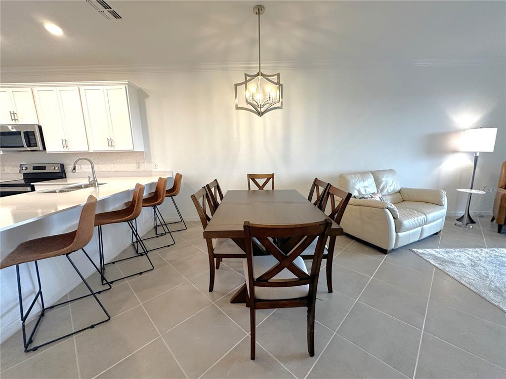 An open-concept dining and living area features tile flooring, a chandelier, and a balcony view — 14121 HERITAGE LANDING BOULEVARD UNIT 743, PUNTA GORDA, FL
