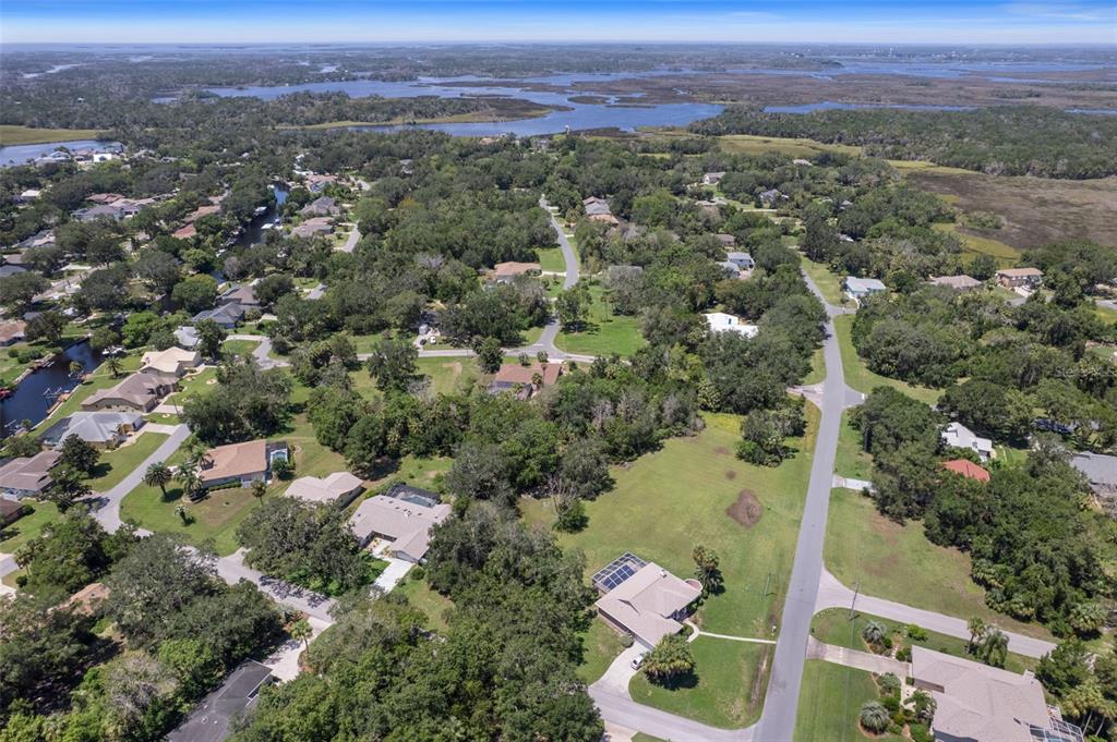 Aerial view of a residential neighborhood with houses, trees, and a nearby body of water — 4788 S WOOD WAY, HOMOSASSA, FL