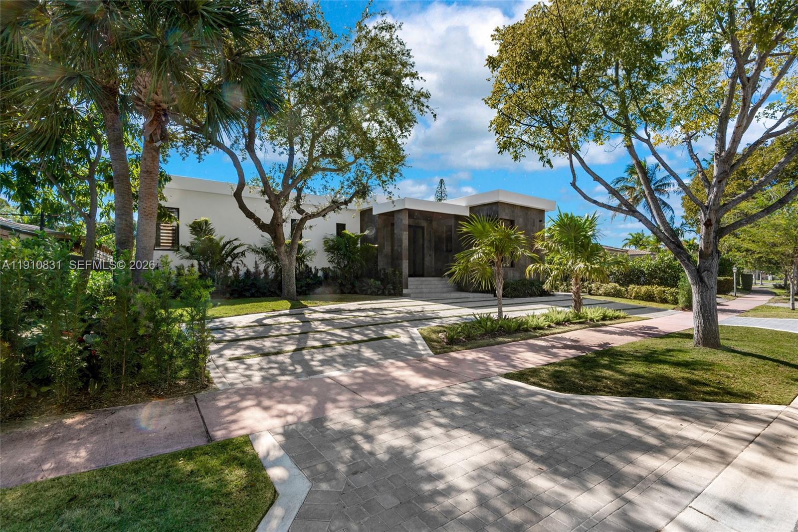 A modern, single-story house with a stone facade and a paved driveway sits among trees — 270 N Shore Dr, Miami Beach FL 33141, MIAMI BEACH, FL