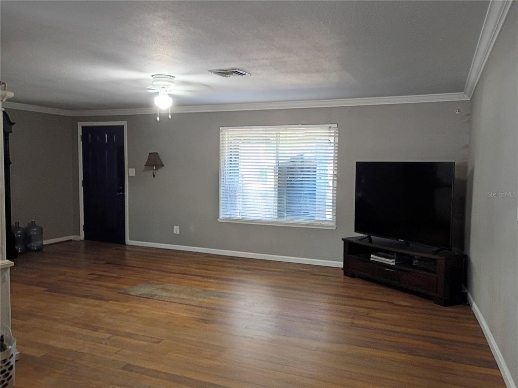 A living room features hardwood floors, gray walls, a ceiling fan, and a television console — 2601 MANATEE HARBOR DRIVE, RUSKIN, FL